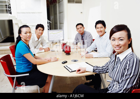 Porträt von zwei Geschäftsfrauen mit drei Geschäftsleute sitzen an einem Konferenztisch Stockfoto