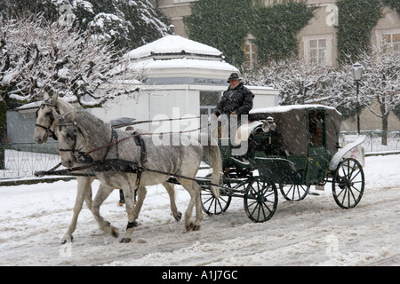 Pferdegespannen Kutschfahrt in einem Schneesturm, Old Town (Altstadt), Salzburg, Österreich Stockfoto