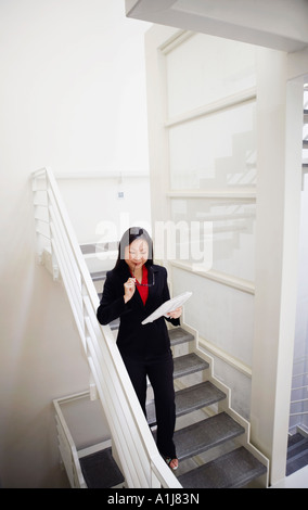 Vogelperspektive Blick auf eine Geschäftsfrau hält eine Zeitung und eine Treppe hinunter Stockfoto