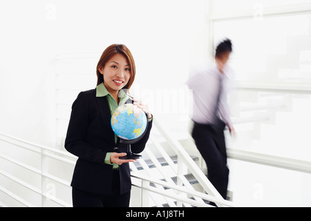 Porträt einer Geschäftsfrau hält einen Globus und lächelnd Stockfoto