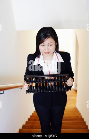 Porträt einer Geschäftsfrau hält einen Abakus und stehend auf der Treppe Stockfoto