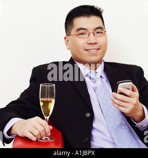 Porträt eines Geschäftsmannes hält ein Champagnerglas und ein Handy Stockfoto