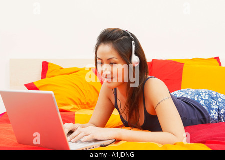 Nahaufnahme einer jungen Frau mit einem Laptop und anhören von Musik über Kopfhörer Stockfoto