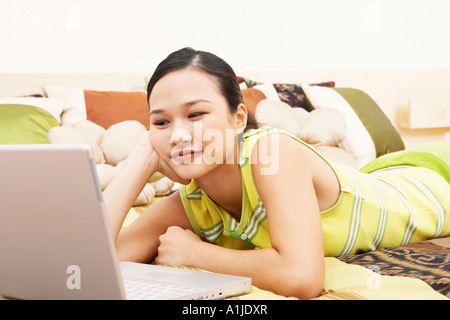 Junge Frau mit Blick auf einen Laptop und denken Stockfoto