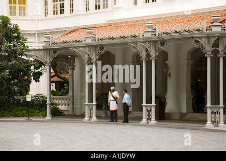 Sikh Türsteher in uniform im Gespräch mit Mann in westlicher Kleidung am Raffles Hotel Eingang Stockfoto