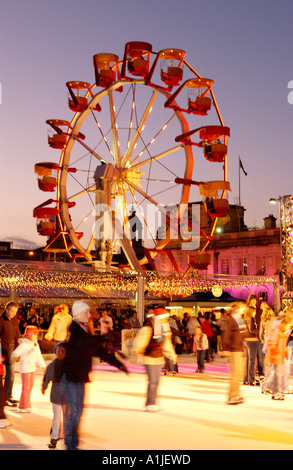 Winter-Wunderland Veranstaltung außerhalb Cardiff City Hall Wales UK mit Menschen Schlittschuhlaufen auf der Eislaufbahn und Riesenrad im Hintergrund Stockfoto