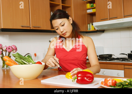 Junge Frau Schneiden von Gemüse auf eine Küchentheke Stockfoto