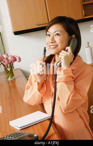 Nahaufnahme einer jungen Frau mit einem Telefon in der Küche Stockfoto