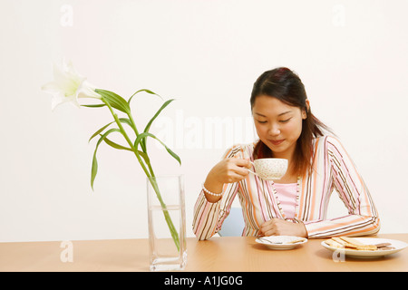 Nahaufnahme einer jungen Frau hält eine Teetasse und lächelnd Stockfoto