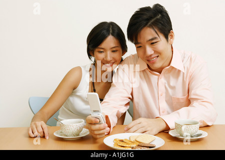 Nahaufnahme eines jungen Paares sitzen und mit Blick auf ein Mobiltelefon Stockfoto