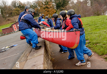 Studenten zeigen Teamarbeit beim Starten eines offenen Kanus am Ufer des Flusses Usk bei Brecon Powys South Wales UK Stockfoto