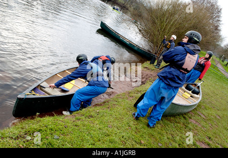 Studenten zeigen Teamarbeit beim starten öffnen Sie Kanus am Ufer des Flusses Usk bei Brecon Powys South Wales UK Stockfoto