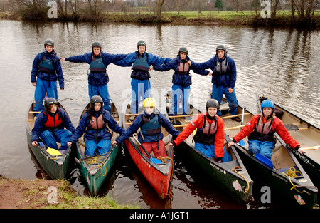 Studenten demonstrieren zuversichtlich Teamarbeit in offenen Kanus auf dem Fluss Usk bei Brecon Powys South Wales UK Stockfoto