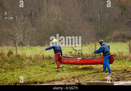 Studenten auf eine Abenteuerreise in öffnen Sie Kanus tragen ein Boot um ein Wehr am Fluss Usk in Brecon Powys South Wales UK Stockfoto