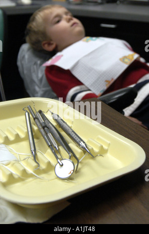 3 jährige junge wartet im Zahnarztstuhl mit Dentalwerkzeuge auf Tisch im Vordergrund Kinderzahnheilkunde Stockfoto