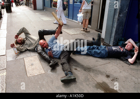 Betrunkene Männer fallen über Rollen auf dem Bürgersteig betrunken. Stockfoto