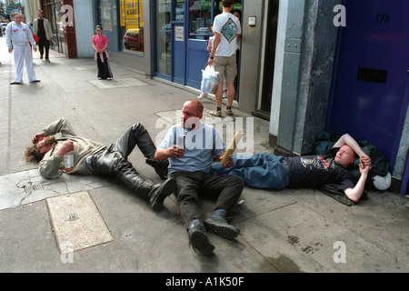 Betrunkene Männer fallen über Rollen auf dem Bürgersteig betrunken. Stockfoto