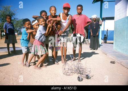 San-Kinder, die spielen mit handgefertigten Spielsachen in der kleinen Stadt Drimiopsis im zentralen östlichen Namibia San-Buschmänner haben eine orientalische Stockfoto