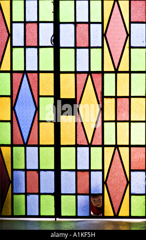 GUATEMALA SAN PEDRO LA LAGUNA indigenen Tzutujil Maya-Kleinkind Jungen spähen durch die gebrochenen Glasmalerei Tür seiner Kirche Stockfoto