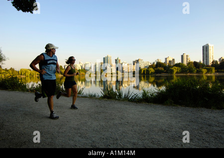 Läufer bei Lost Lagoon im Stanley Park mit der Skyline von Vancouver hinter, Vancouver BC, Kanada Stockfoto