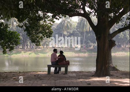 Ein paar sitzt auf einer Bank im Ramna Park in Dhaka, Bangladesch Stockfoto