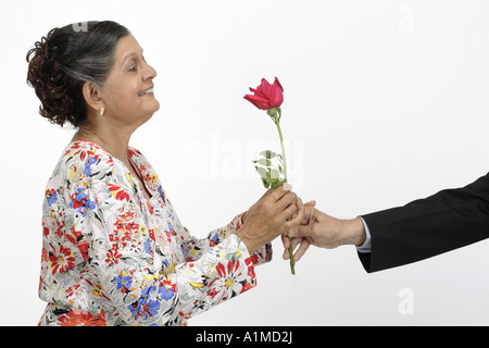 Alte Frau, die eine rote Rosenblume erhält - HERR# Stockfoto