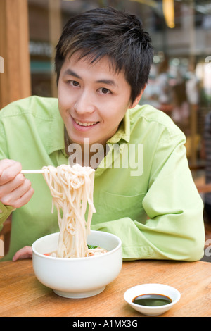 Junger Mann essen Nudeln Stockfoto