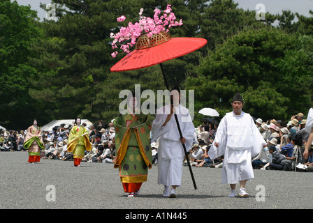 Teilnehmer am Aoi Matsuri Festival laufen mit einem roten Regenschirm tragen 6.Jahrhundert Kostüm in Kyoto Japan Asien Stockfoto