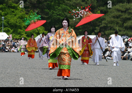 Teilnehmer an dem bunten Aoi Matsuri Festival laufen mit einem kultigen roten Regenschirm 6.Jahrhundert Kostüm in Kyoto Japan Stockfoto