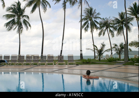 Einsame junge weibliche Schwimmer träumt und blickt auf das Meer aus einem Pool in einem Luxus-Resort auf der tropischen Insel Langkawi Malaysia Stockfoto