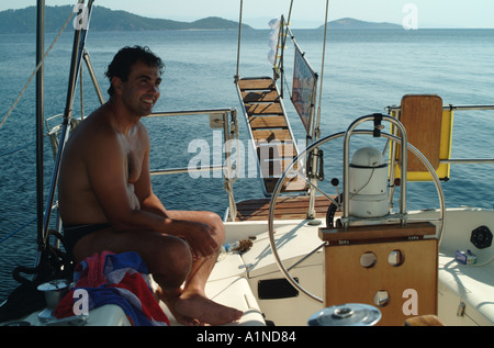 junger Mann an Bord verankerte Segelyacht entspannend Stockfoto