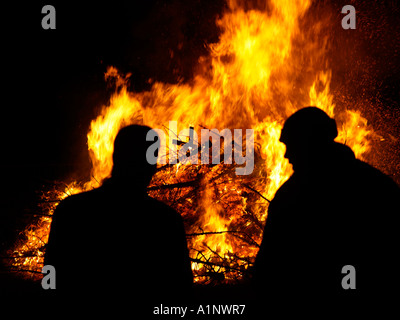 zwei Männer Silhouette vor ein riesiges Feuer Feuer aus der Verbrennung von alten Weihnachtsbäume ein Brauch in den Niederlanden Anfang Januar Stockfoto