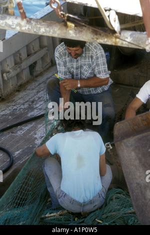 Zwei Fischer reparieren ihre Netze auf einem Fischerboot im Hafen von Vrsar, Kroatien. Stockfoto