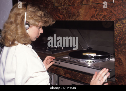 12-jährige Teenager Mädchen im Jahr 1980s trägt Kopfhörer hören Auf Vinyl-Schallplatte abspielen on1984 JVC Stereo Plattenspieler Deck zu Hause England UK Stockfoto