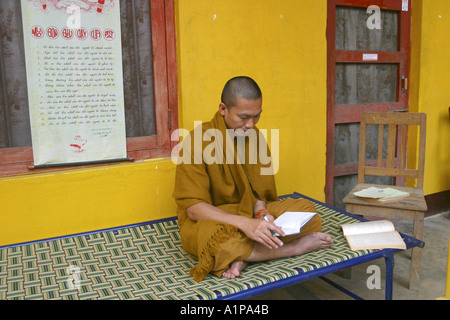 Ein thailändischer buddhistischer Mönch liest in einem Buch außerhalb seines Klosters in Sarnath in Uttar Pradesh in Indien Stockfoto