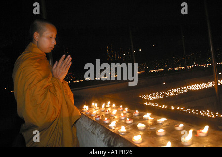 Ein thailändischer buddhistischer Mönch betet, neben einer Reihe von Kerzen an der Mahabodhi-Tempel in Bodhgaya in Bihar in Indien Stockfoto