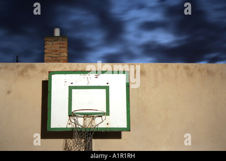 Ein alter Basketballkorb an einer verwitterten Wand unter einem dramatisch bewölkten Nachthimmel. Stockfoto