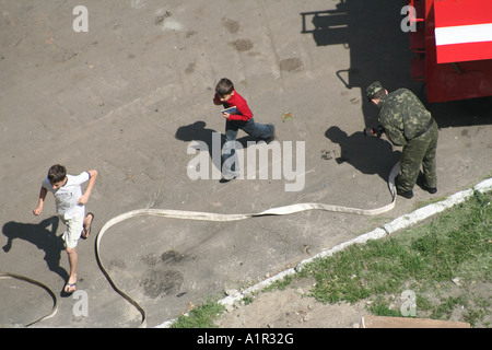 Kinder, die während einer Notfallreaktion in Kiew, Ukraine, an einem Feuerwehrmann vorbeilaufen. Stockfoto