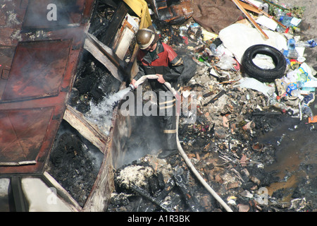 Feuerwehrmann vergießt Flammen inmitten von Trümmern und Rauch in Kiew, Ukraine. Stockfoto