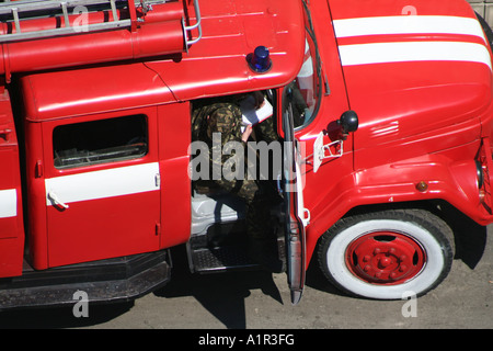 Feuerwehrmann in Uniform sitzt in einem roten Feuerwehrauto und bereitet sich auf die Aktion in Kiew, Ukraine vor. Stockfoto