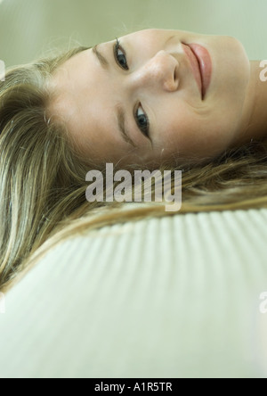 Junge Frau liegend, lächelnd in die Kamera, Nahaufnahme des Gesichts Stockfoto