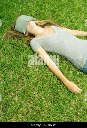 Junge Frau liegt auf dem Rasen mit Augenkissen Augen bedecken Stockfoto