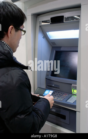 Paris, Frankreich, asiatische Jüngling, Bargeld von A.T.M Geldautomaten bei der Bank mit Kreditkarte Stockfoto