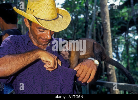 1 einem brasilianischen Mann spielt mit Kapuziner Affen entlang Ariau Fluss im Amazonas Regenwald im Amazonas, Brasilien, Südamerika Stockfoto