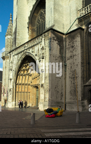 Ein junger Mann saß auf einem gelben Sofa vor der Kathedrale in Gent Begian Stockfoto