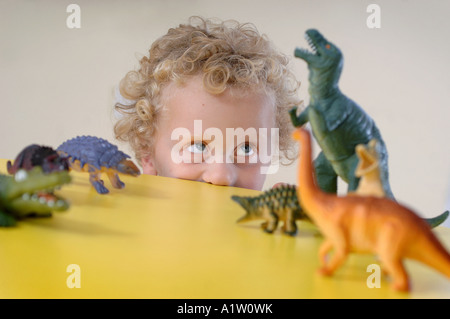 Ein kleiner Junge spielt mit Dinosauriern in einem Kindergarten Stockfoto