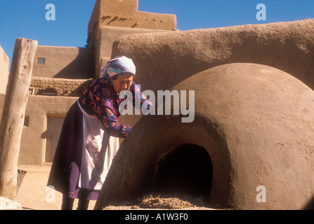 Taos New Mexico eine Frau Reparaturen im freien Adobe Ofen zum Backen von Brot, Fleisch und Kuchen in Taos Pueblo Stockfoto