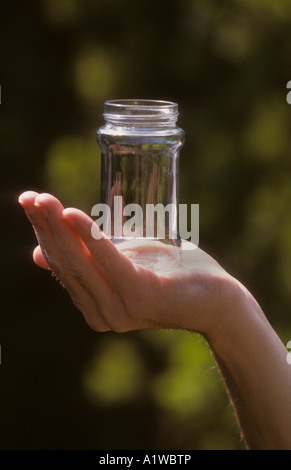 Mans Hand mit einem leeren Glas, draußen bei Tageslicht. Stockfoto