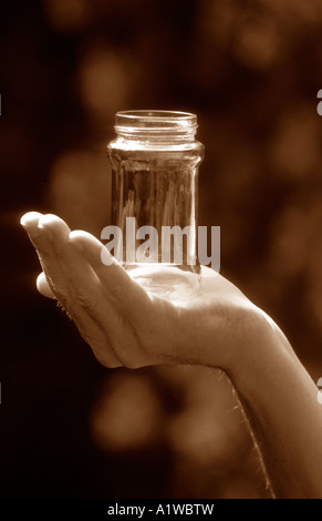 Mans Hand mit einem leeren Glas, draußen bei Tageslicht. Stockfoto