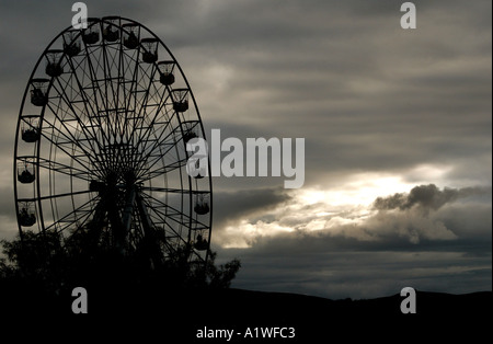 Eine Silhouette ein Riesenrad mit stürmischen Wolken im Hintergrund fast monotone Stockfoto